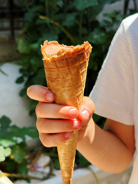 Child Holding Partially Eaten Ice Cream Cone in Sunlight