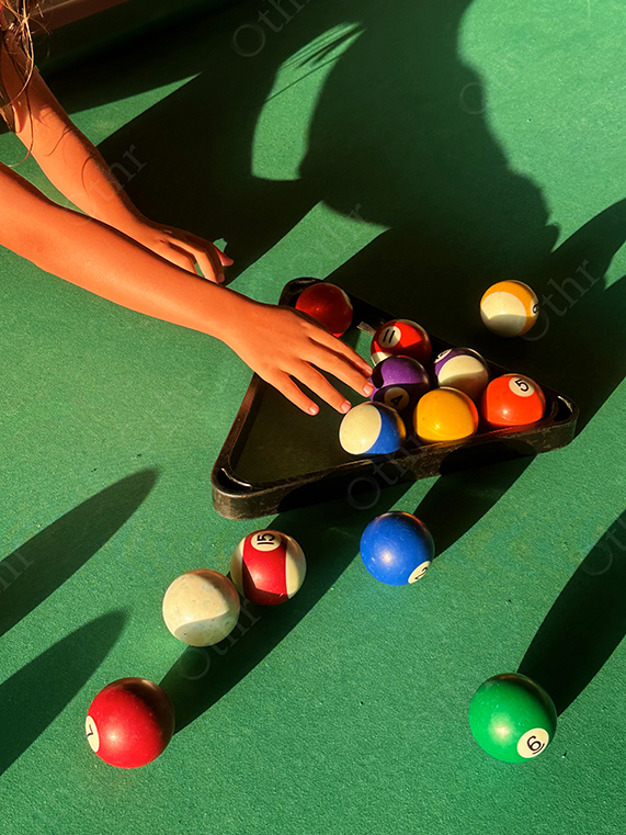 Child’s Hand Arranging Colourful Billiard Balls on Green Pool Table