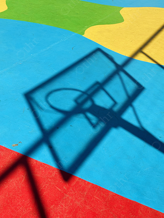 Shadow of Basketball Hoop Cast on Colourful Outdoor Court
