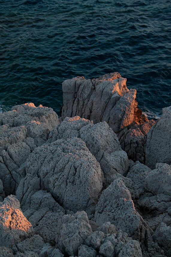 Rocky Coastal Cliffs Illuminated by Sunset Beside Deep Blue Sea