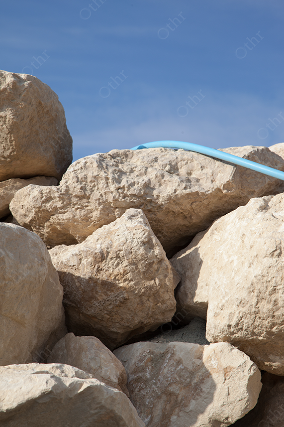 Large Beige Rocks With Blue Pipe Under Clear Sky