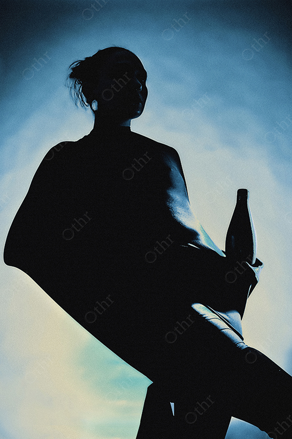 Silhouetted Woman Holding a Bottle Against Blue Backlit Background