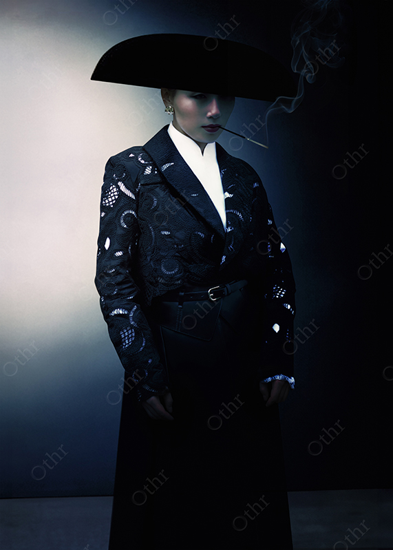 Person in Wide-Brimmed Hat and Lace Jacket Smoking Under Moody Studio Light