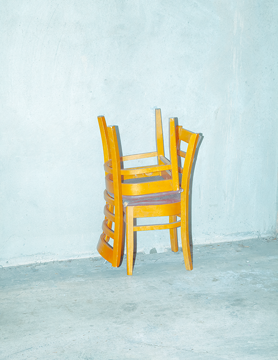 Stacked Wooden Chairs Against a Pale Concrete Wall