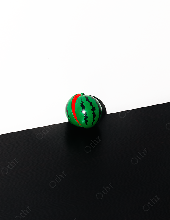 Green and Red Toy Watermelon Ball on Black and White Surface