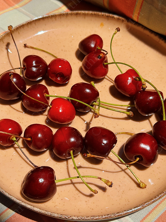 Fresh Cherries Spread on a Ceramic Plate in Sunlight