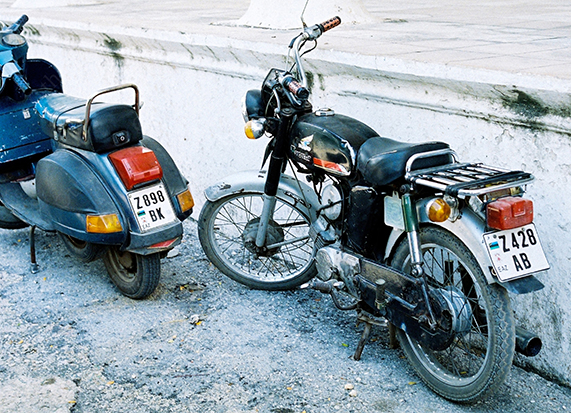 Vintage Motorbike and Scooter Parked Beside a Concrete Wall