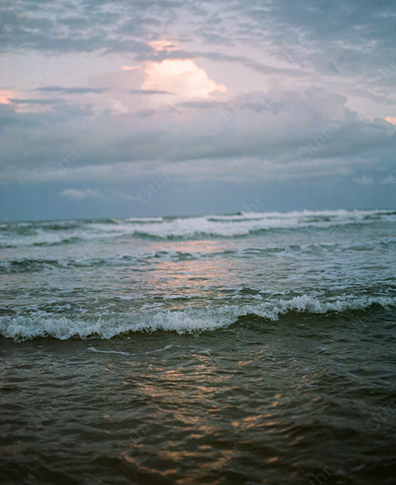 Waves Breaking Along a Cloudy Coastline at Sunset