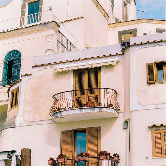 Sunlit Mediterranean Building With Shuttered Windows and Curved Balcony