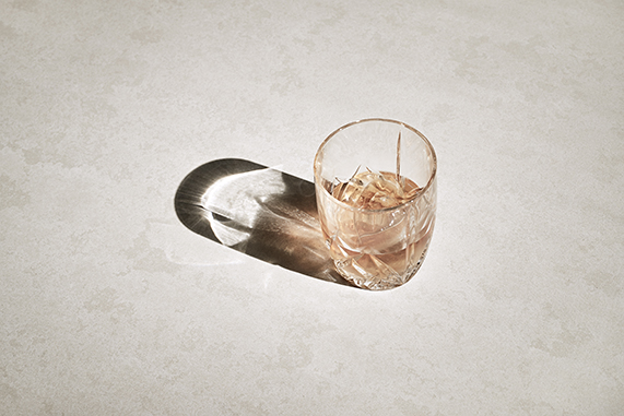 Glass of Iced Drink Casting a Soft, Elongated Shadow in Warm Sunlight