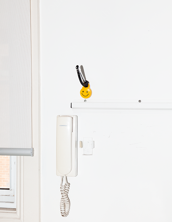 White Wall Intercom Beneath a Smiley-Face Keychain on a Hook