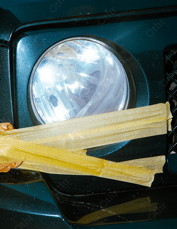 Car Headlight Partially Covered With Yellow Masking Tape