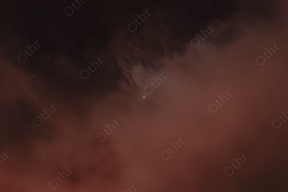 Bright Star Emerging Through Dark Clouds at Night