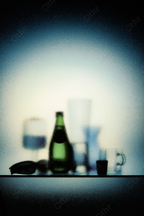 Out-Of-Focus Glassware and Green Bottle Arranged on Shelf Against Blue Gradient Background
