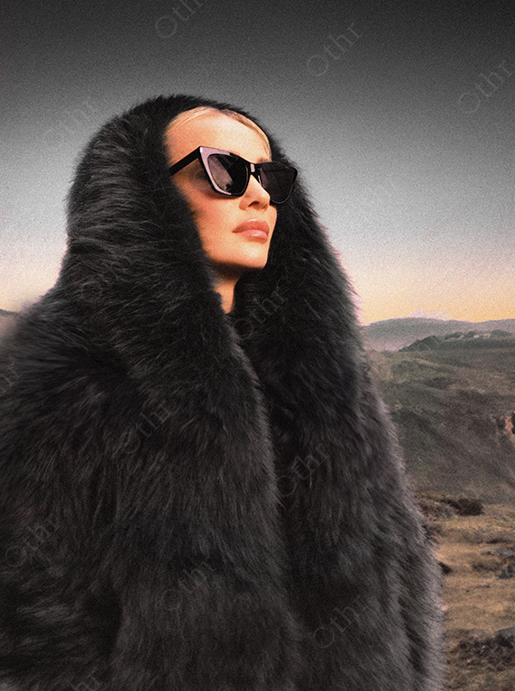 Portrait of Woman Wearing Dark Sunglasses and Fur Coat Standing Outdoors Against Distant Hills at Dusk