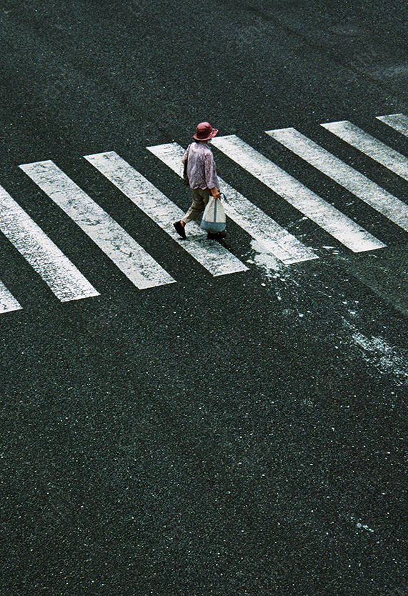 High-Angle View of Pedestrian Crossing Zebra Lines on Dark Asphalt Road
