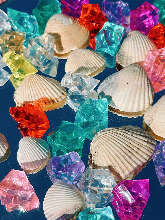 Seashells Scattered Among Colourful Acrylic Crystals on Blue Background