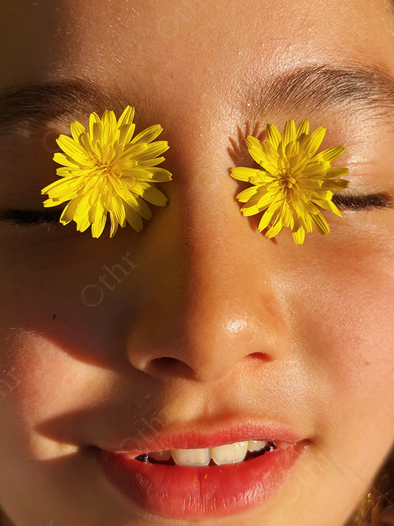 Close-Up Portrait of Woman With Yellow Flowers Covering Eyes in Warm Sunlight