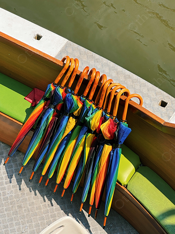Colourful Umbrellas With Curved Handles Lined Up on Boat Deck Beside Water