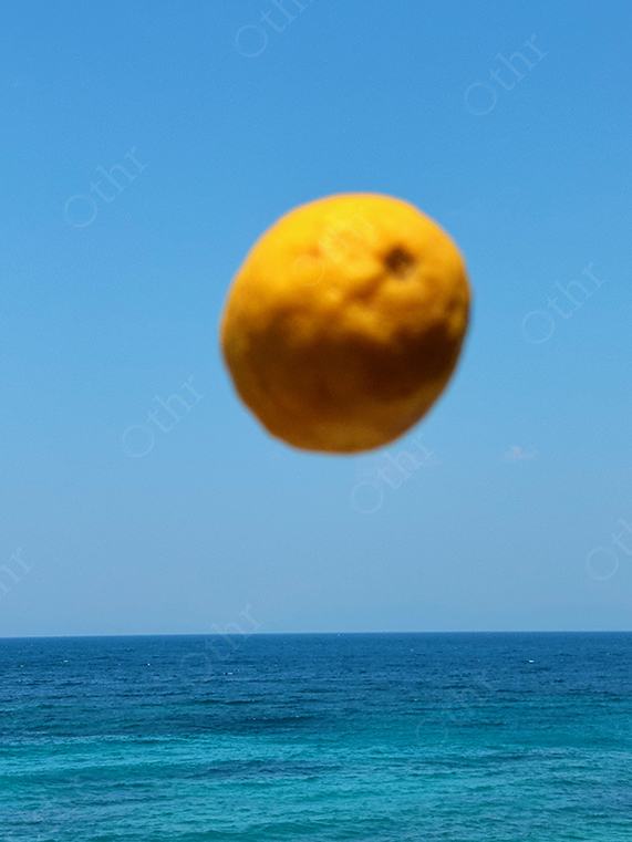 Floating Lemon Suspended Above Calm Blue Sea Against Clear Sky