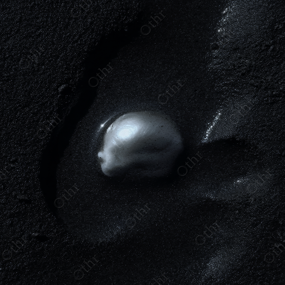 Baroque pearl set in black sand.