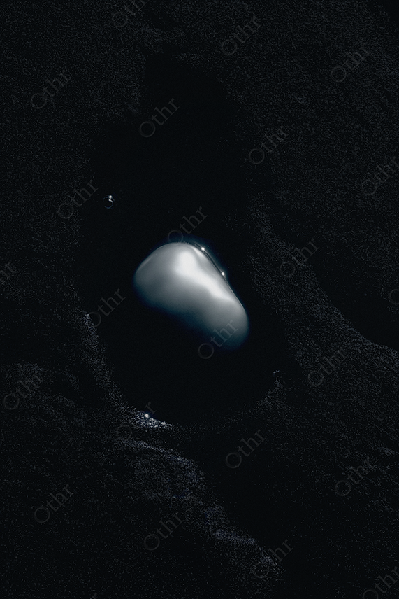 Baroque pearl set in black sand.