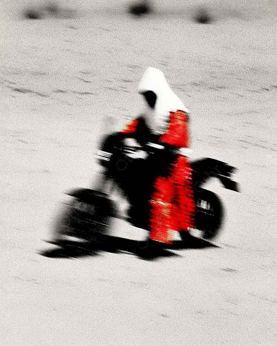 Hooded desert rider on motorcycle in white sandscape.