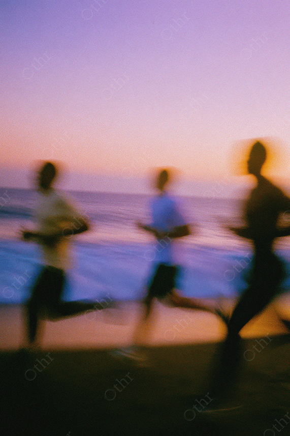 Group jogging along ocean at dusk with motion blur