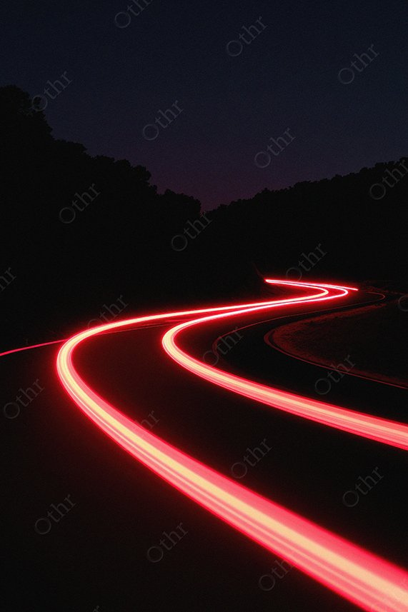 Long-exposure red light trails bending through night highway