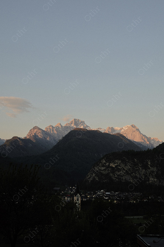 Alpine Village Beneath Mountain Range Lit by Soft Evening Light
