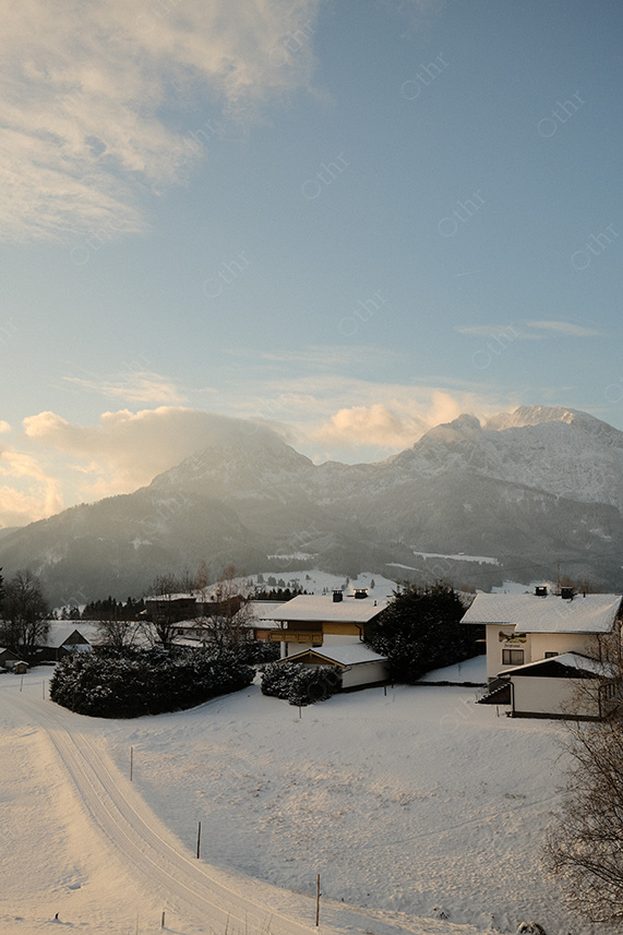 Snow-Covered Alpine Village Beneath Mountain Peaks in Soft Morning Light