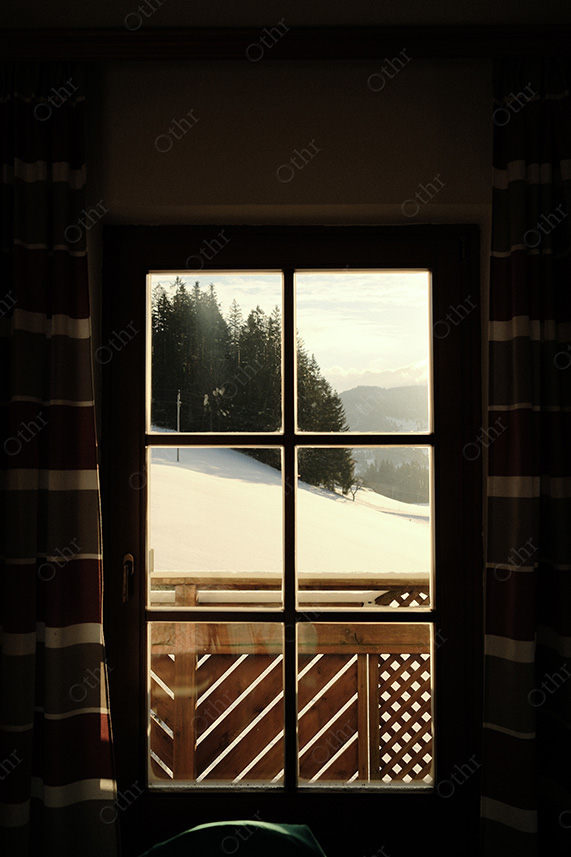 Snowy Hillside Viewed Through Cabin Window With Mountain Landscape Beyond