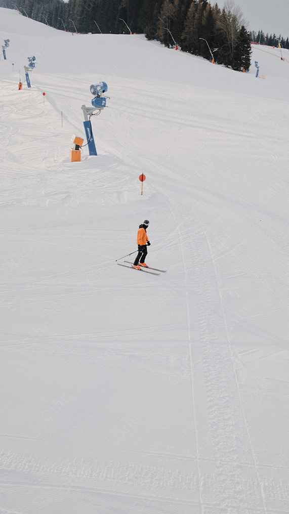 Skier Descending Groomed Slope on Snow-Covered Mountain