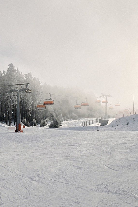 Empty Ski Lift Line Over Snowy Slope in Soft Winter Light