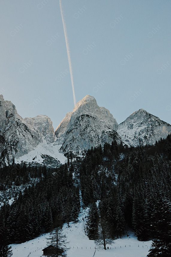 Jagged Snow-Capped Mountain Peaks Rising Above Dense Forest