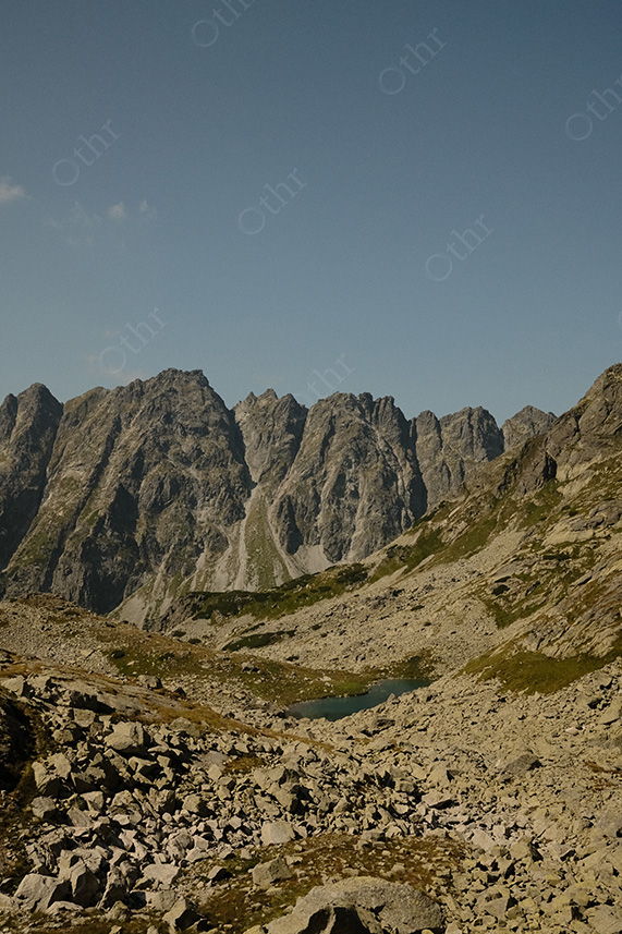 Rocky Alpine Basin With Small Mountain Lake Below Jagged Peaks