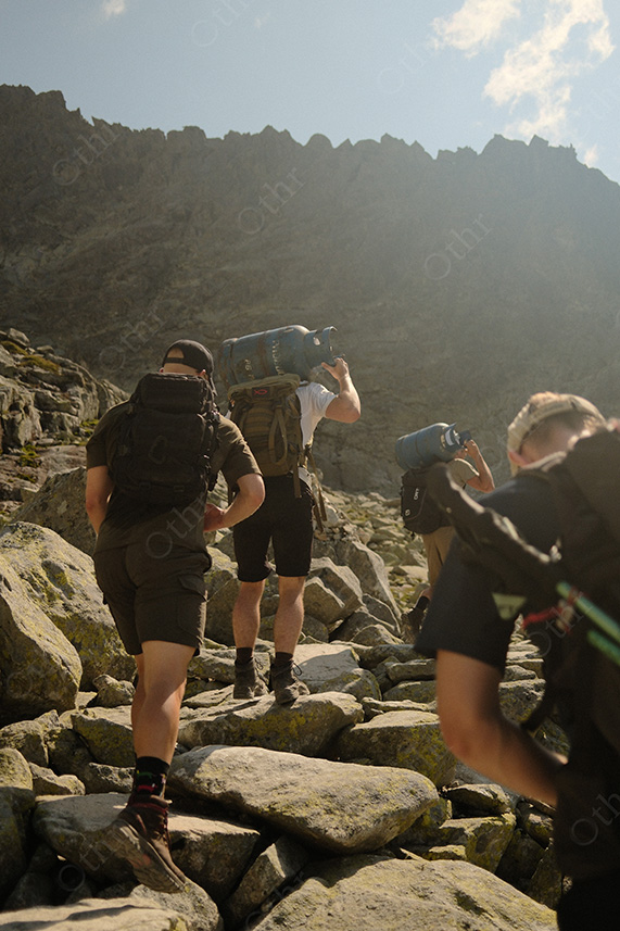 Hikers Climbing Rocky Mountain Trail With Backpacks in Harsh Sunlight