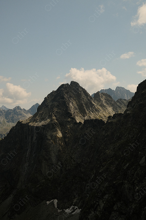 Dark Mountain Ridge Silhouetted Against Bright Sky with Distant Peaks