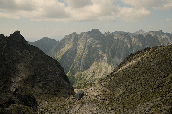 Mountain Trail Leading to Small Hut Between Steep Rocky Slopes