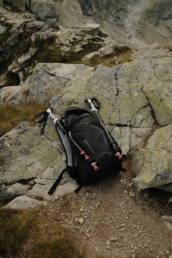 Backpack and Trekking Poles Resting on Lichen-Covered Rocks
