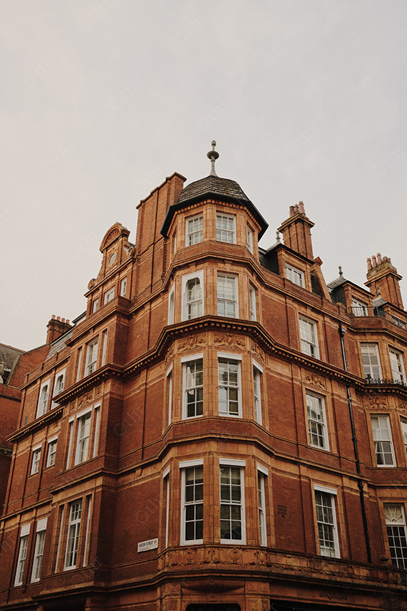 Low-Angle View of Red Brick Corner Building Against Overcast Sky