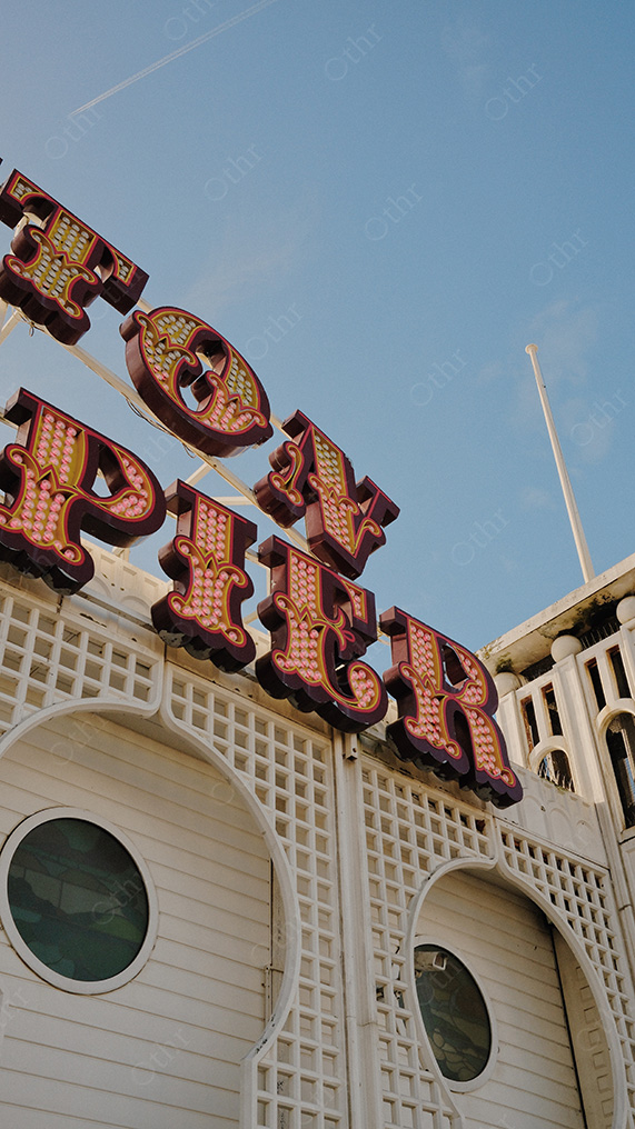 Vintage Fairground Sign Reading “Top Spin” Mounted on Decorative White Building Facade Against Blue Sky