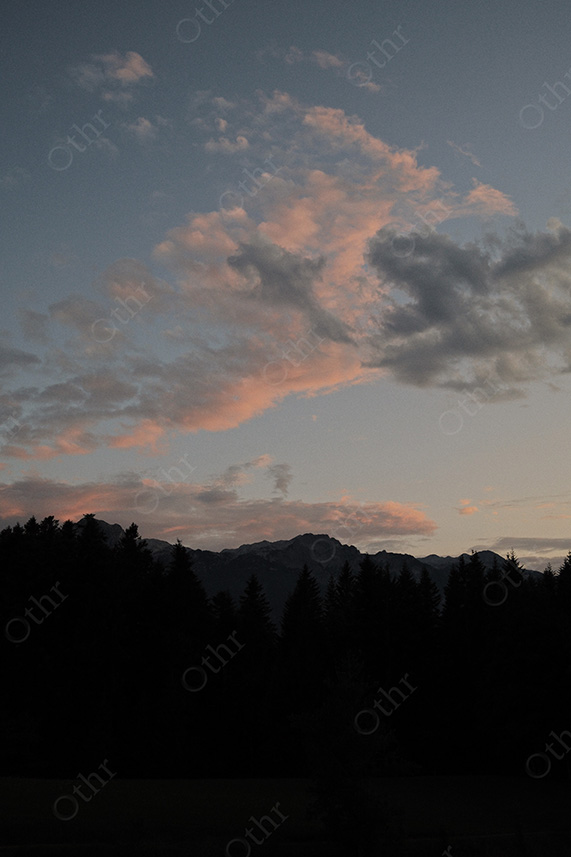 Mountain Ridge and Tree Line in Silhouette Beneath Soft Evening Clouds