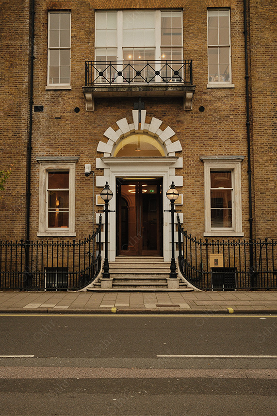 Symmetrical Brick Townhouse Entrance With Arched Fanlight and Iron Railings on Quiet Street