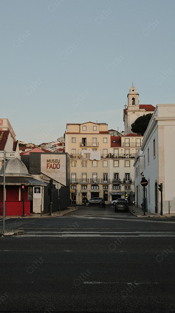 City Street View Toward Building With “Museu Fado” Sign and Hillside Apartments Under Clear Sky