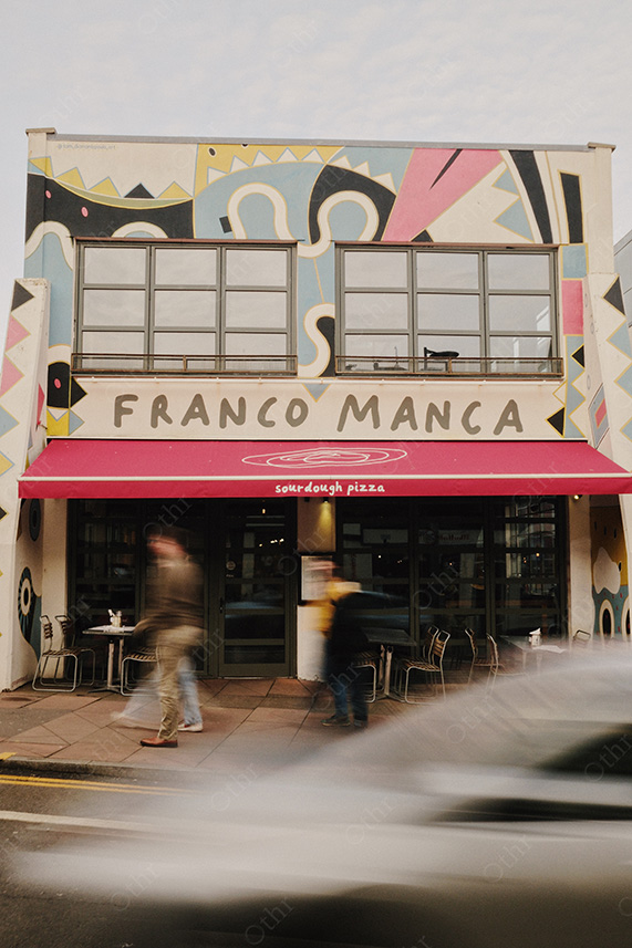 Franco Manca Pizzeria Shopfront With Painted Mural and Passing Pedestrians in Motion Blur