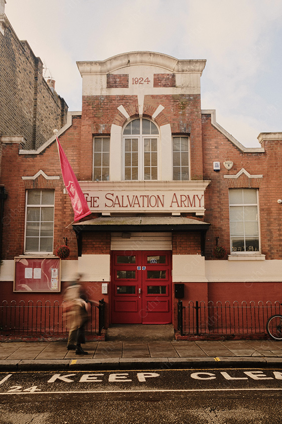 The Salvation Army Building With Red Doors and Flag on Street With Motion Blur Pedestrian