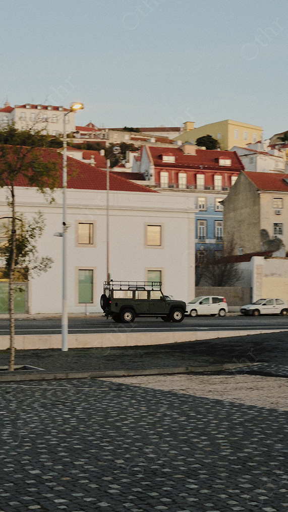 Hillside Houses With Red Tile Roofs Above Roadside Cars in Soft Evening Light