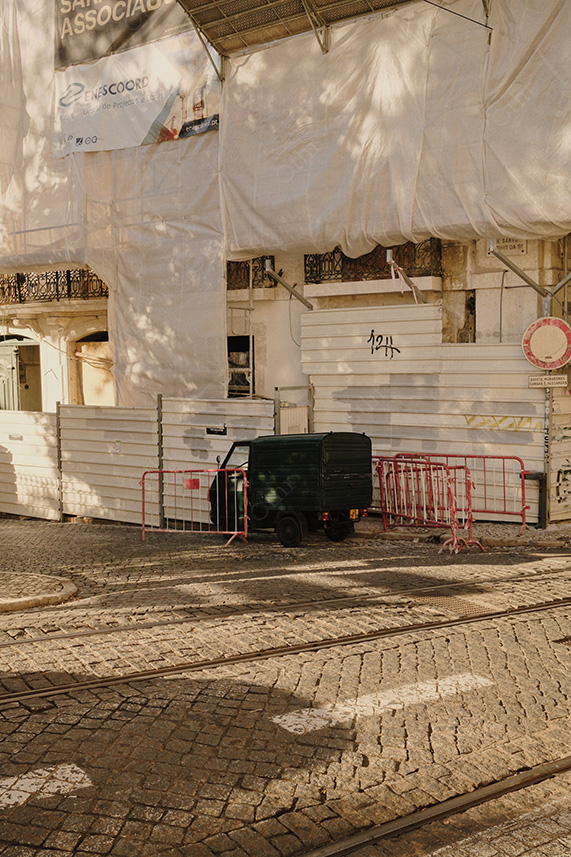 Construction Site Wrapped in White Sheeting With Barriers and Cobblestone Street in Warm Light