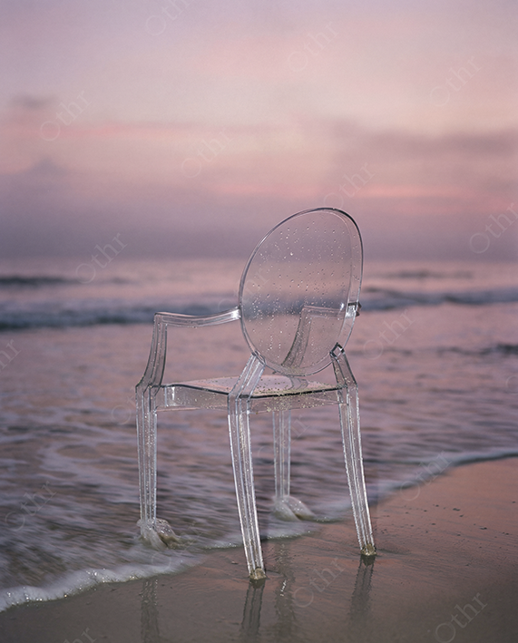 Transparent Acrylic Chair Standing in Shallow Ocean Water at Sunset